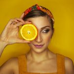 woman covering her right eye with orange slice